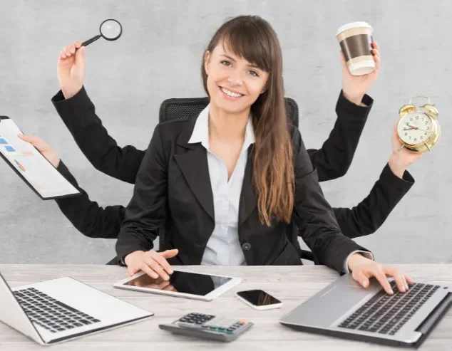 Femme d'affaires multitâche utilisant plusieurs appareils à un bureau.