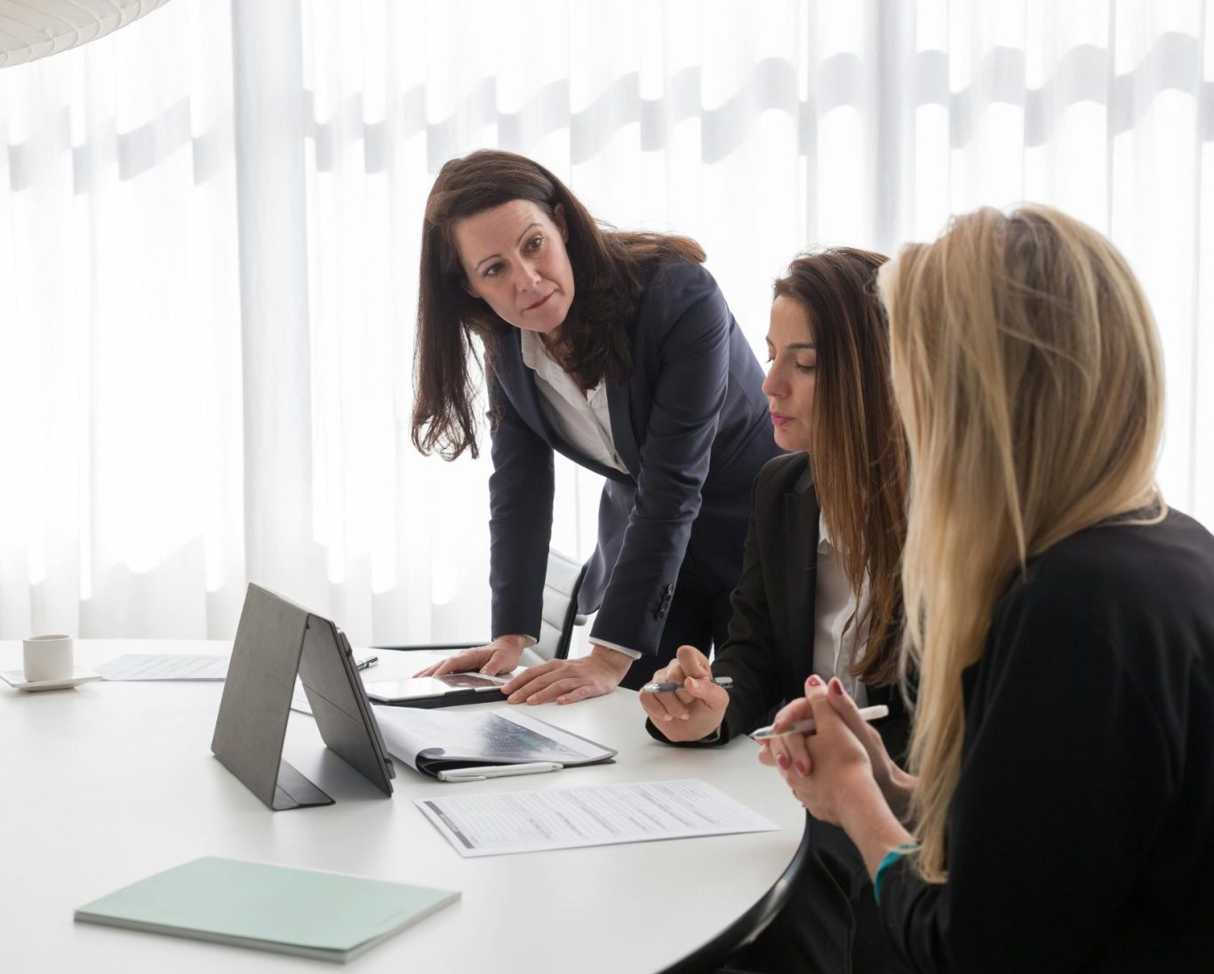 Trois femmes en réunion, discutant autour d'une table avec un ordinateur portable.