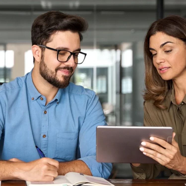 Deux personnes, un homme et une femme, discutent ensemble en regardant une tablette.