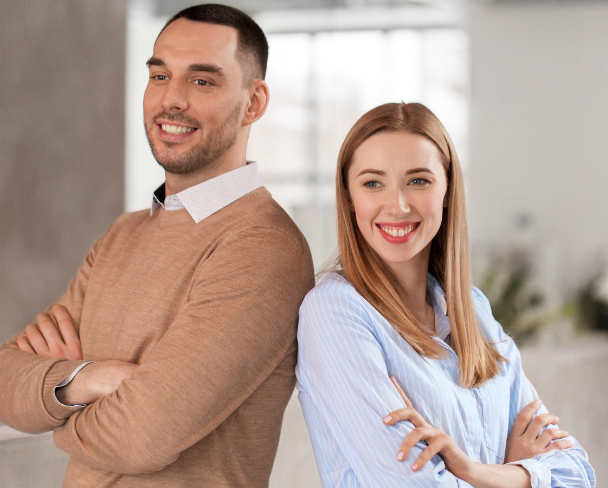 Homme et femme souriants, bras croisés, en arrière-plan lumineux et moderne.