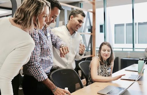 Quatre personnes collaborant autour d'un ordinateur dans un bureau moderne.