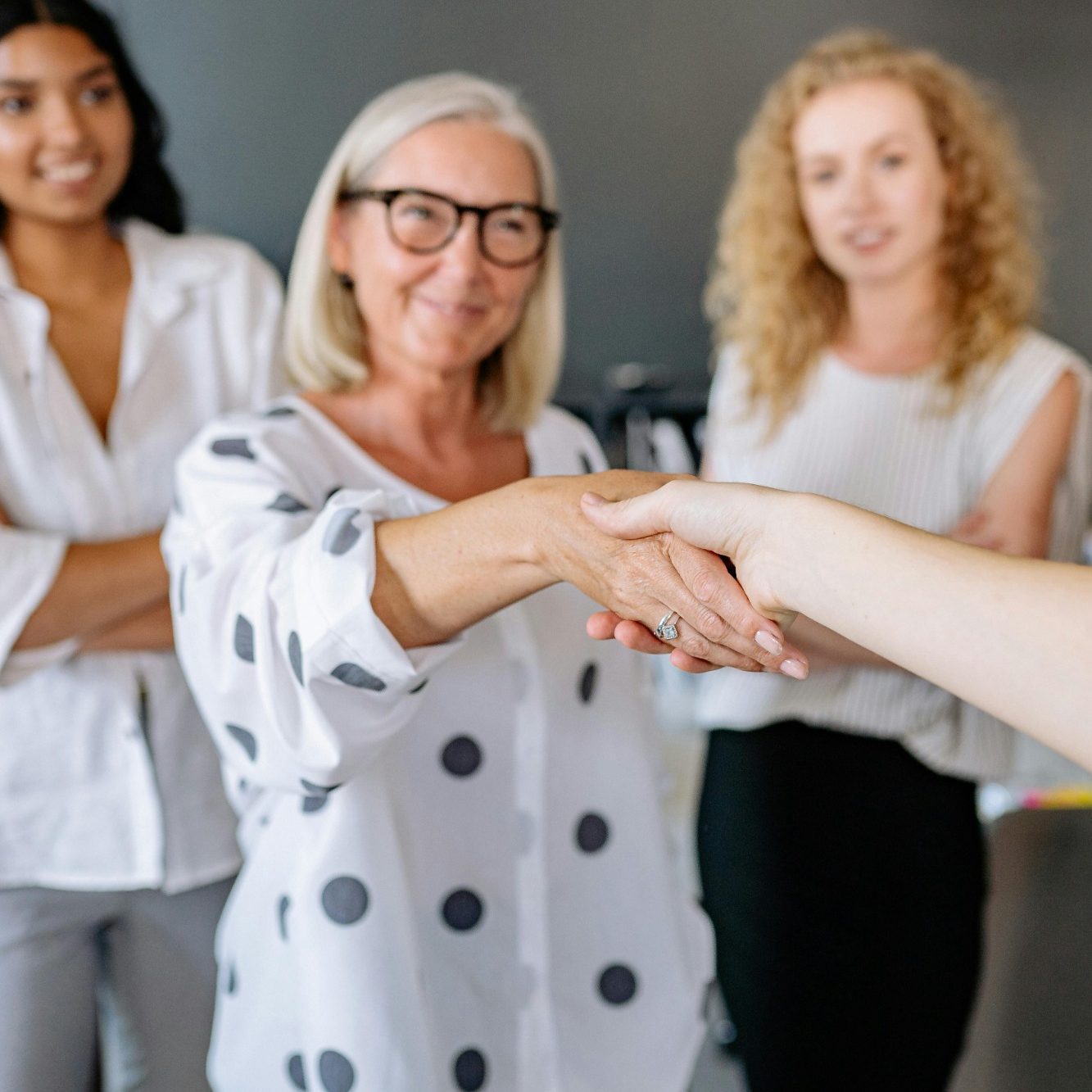 Cinq personnes souriantes se serrent la main dans un environnement professionnel.