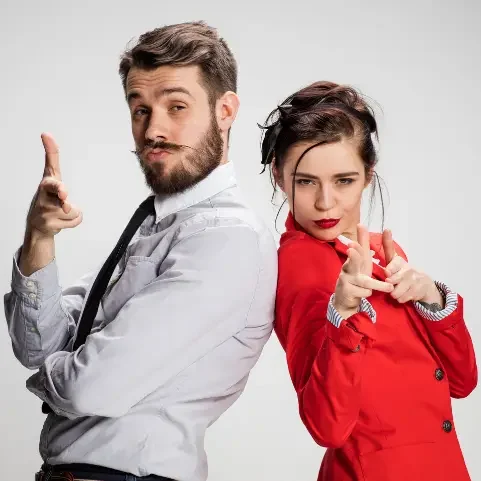 Deux personnes posant en faisant des gestes de "tir" avec les mains, sourires confiants.